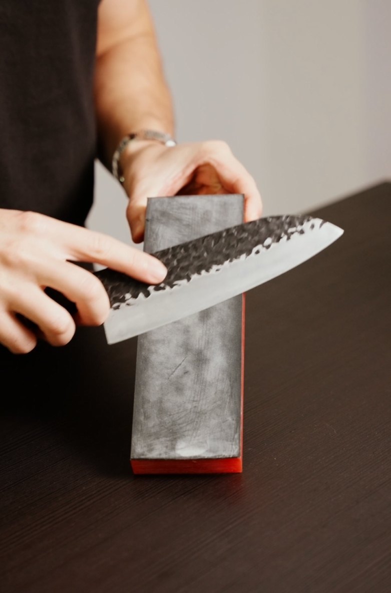 Cuchillo japonés sobre piedra de afilar durante la corrección inicial